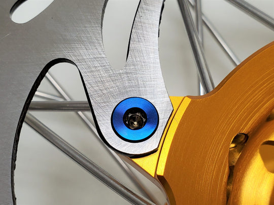 Burnt blue titanium rotor bolt holding a brake rotor to a gold anodized hub