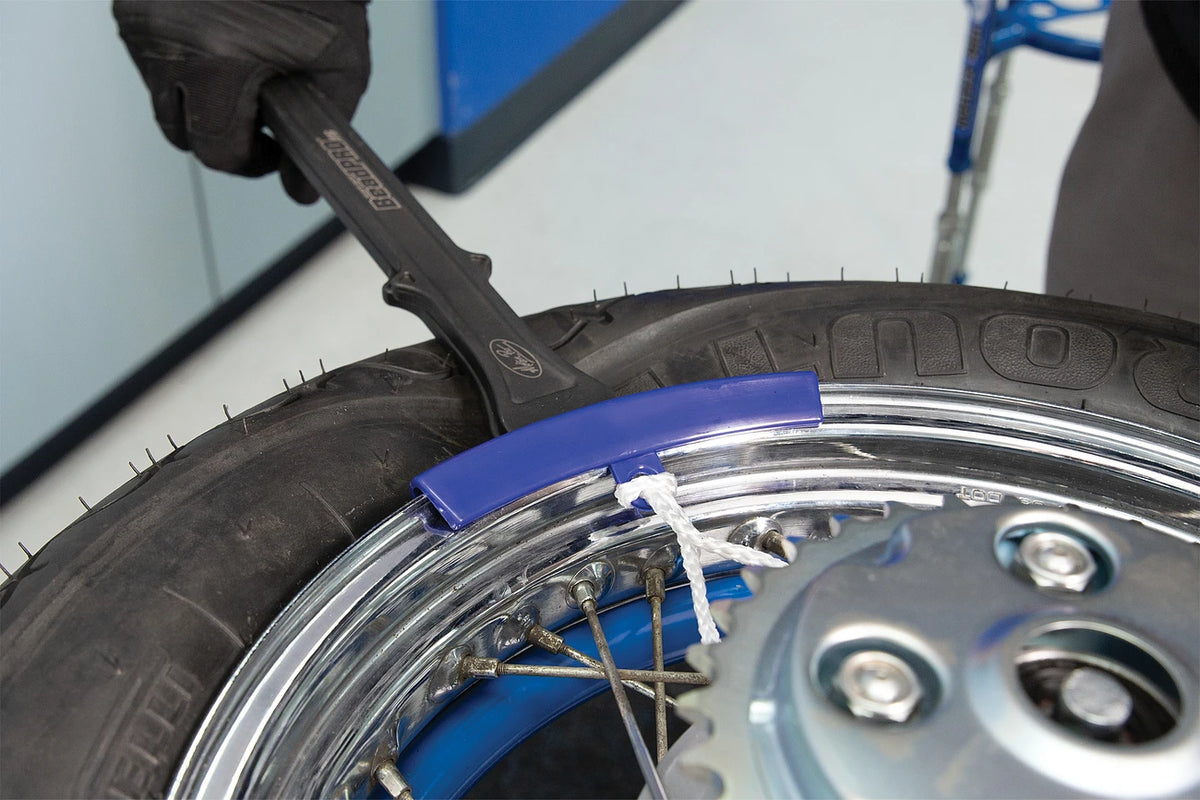 Motion Pro rim protector clipped on a spoked rim while a tire lever mounts the tire