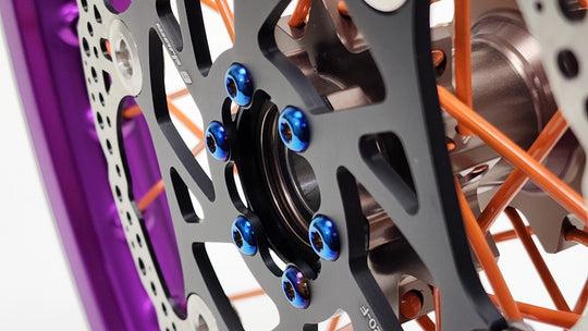 Warp 9 burnt blue titanium rotor bolts installed through a boost spacer on an e-moto front hub