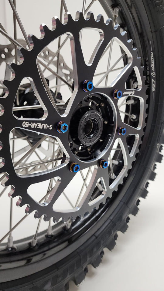 Burnt blue titanium sprocket bolts holding a black Warp 9 sprocket on an e-moto rear wheel